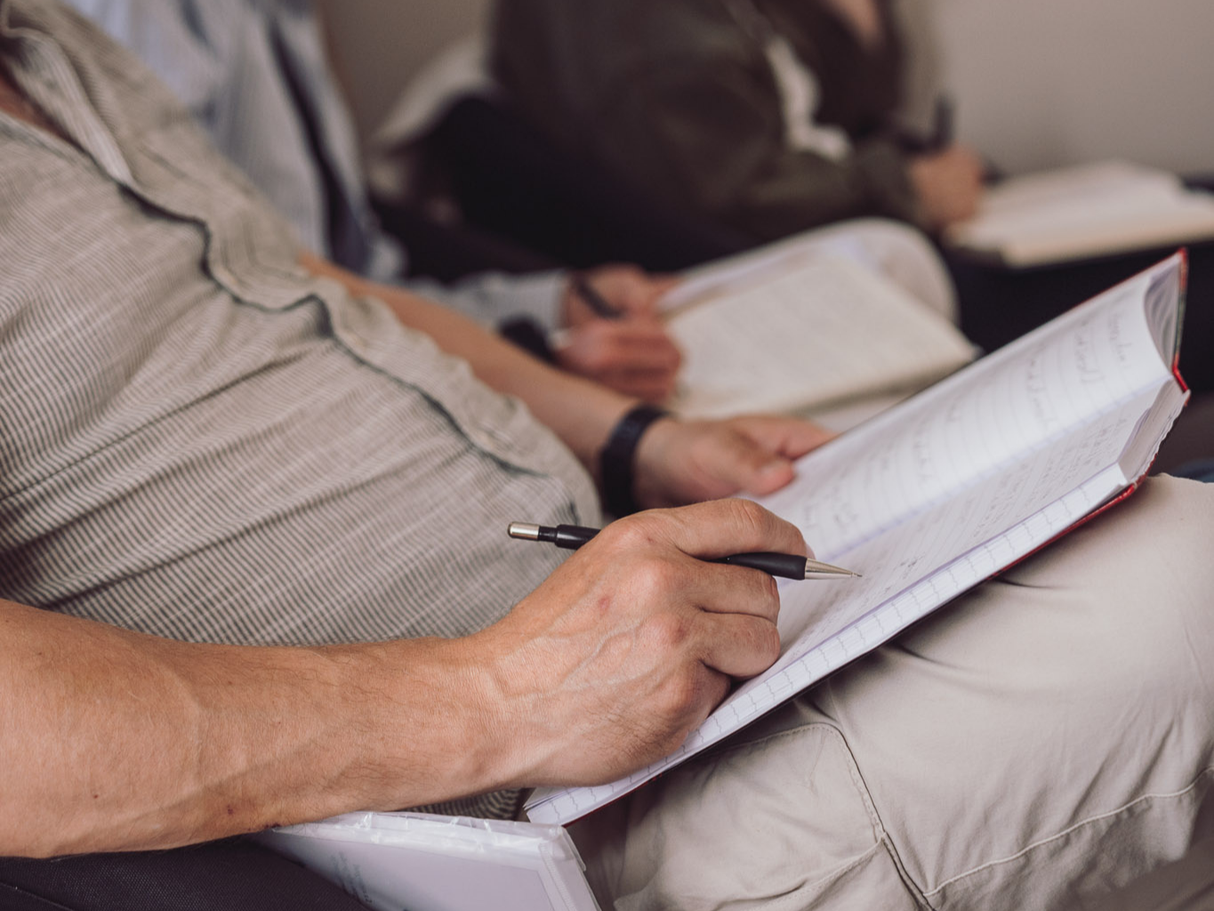 Deltager sidder med notesbog og pen under undervisning på Tobias‑Skolen, hvor der arbejdes med teoretisk læring og refleksion i et roligt undervisningsmiljø.