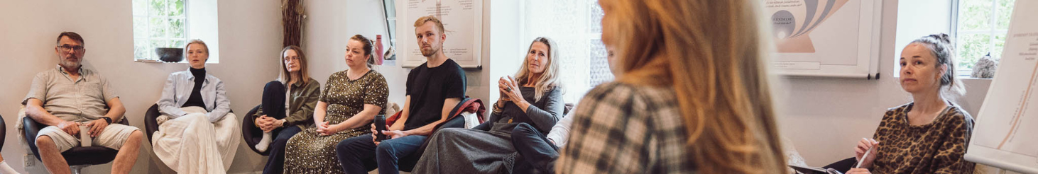 Person på psykoterapeutuddannelse der skriver refleksioner i en notesbog i rolige, grønne omgivelser – stemningsbillede der formidler fordybelse, personlig udvikling og det nærværende læringsmiljø på Tobias‑Skolens psykoterapeutuddannelse og efteruddannelser.