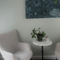 Roligt terapilokale med to komfortable stole, et lille bord og grøn plante – illustrerer de trygge og professionelle rammer for samtaler, personlig udvikling og undervisning på Tobias‑Skolens psykoterapeutuddannelse og efteruddannelser.