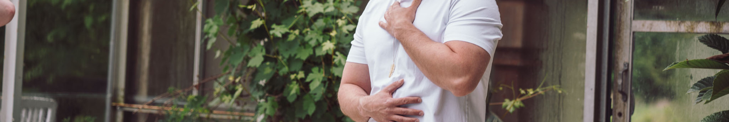 Person i mindful kropsøvelse med hænderne på bryst og mave i grønne, rolige omgivelser – illustrerer nærvær, selvkontakt og terapeutisk arbejde som på Tobias‑Skolens psykoterapeutuddannelse og efteruddannelser.