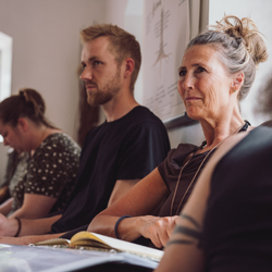 Deltagere sidder i undervisningslokale og fordyber sig i psykoterapeutisk teori og refleksion – stemningsbillede der viser læring, nærvær og faglig udvikling på Tobias‑Skolens psykoterapeutuddannelse og efteruddannelser.